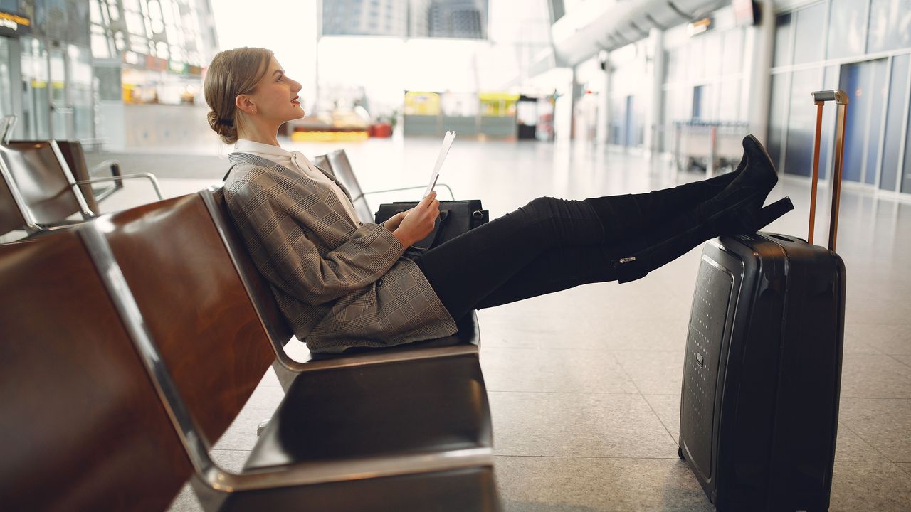 Viajera leyendo una tablet en una sala de espera de aeropuerto