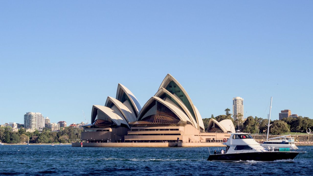 The Sydney Opera House seen from the harbour on a clear day, with a boat passing in the foreground