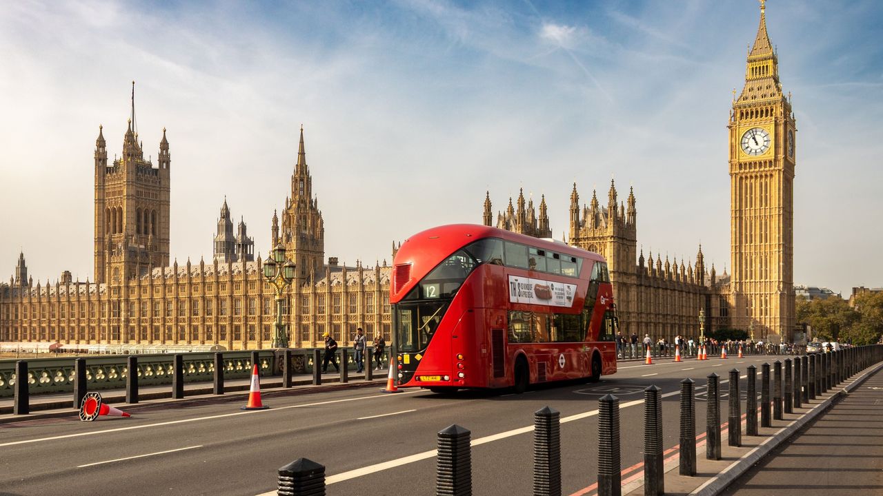 A red double decker bus on Westminster Bridge in front of Big Ben, London