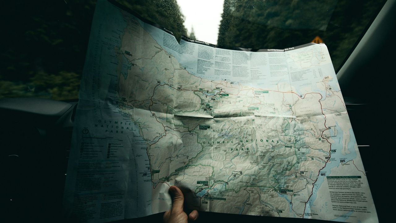 Viajero sosteniendo un mapa de papel mientras planea su ruta