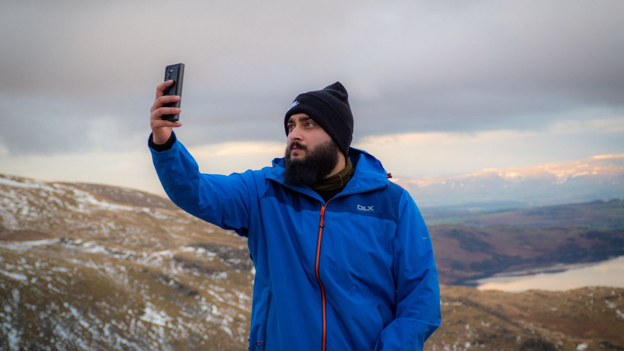 Hiker on a mountain holding a phone up to look for signal