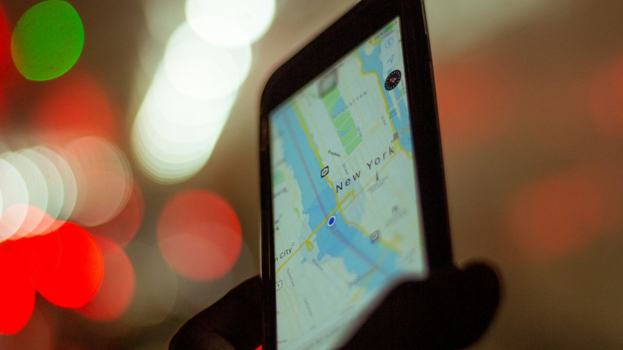 Person holding a smartphone with a map app open on a city street