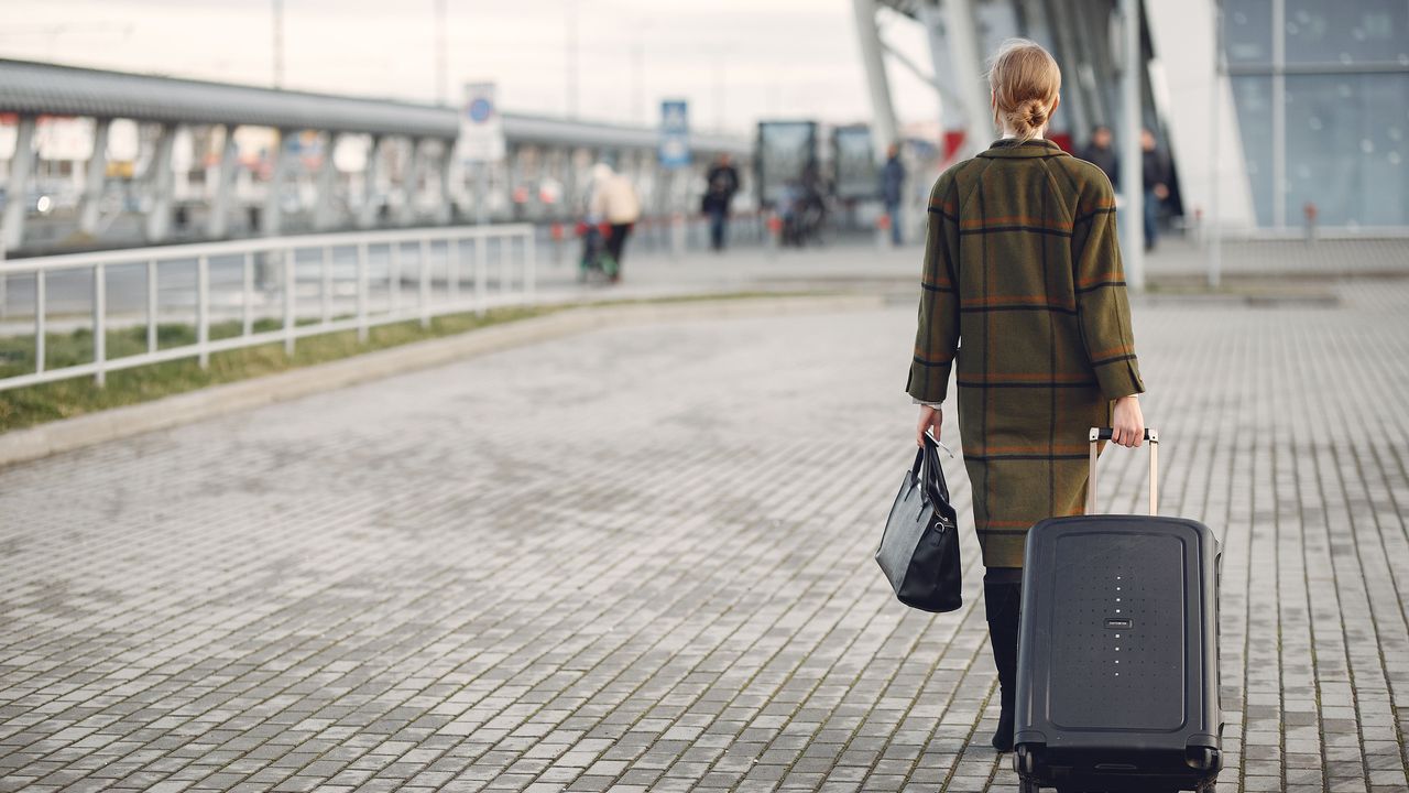 Traveller walking with a suitcase outside an airport terminal