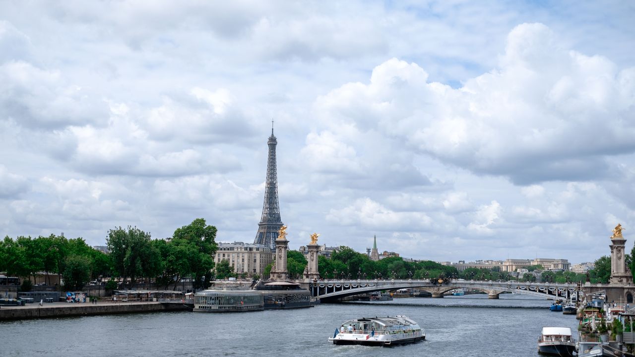 La Torre Eiffel y el Sena en París en un día luminoso, con un barco pasando bajo el puente
