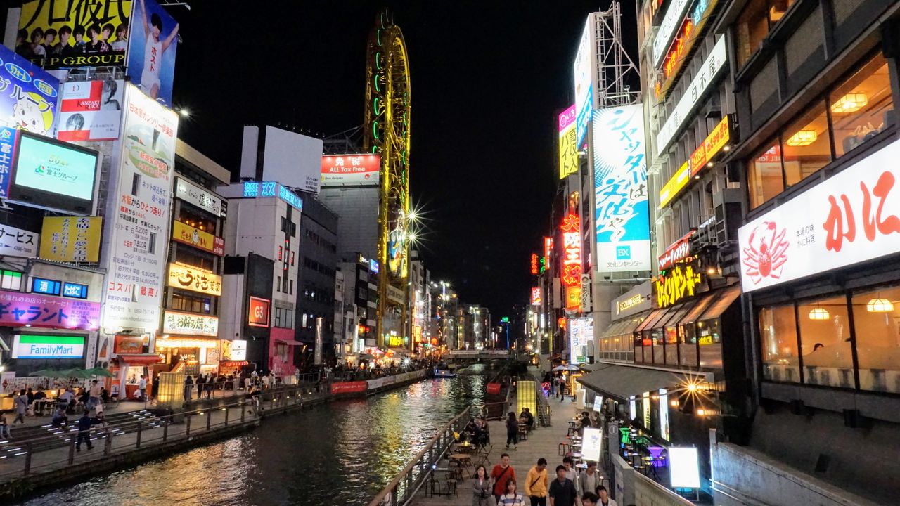 El canal de Dotonbori en Osaka de noche, con letreros de neón y gente caminando