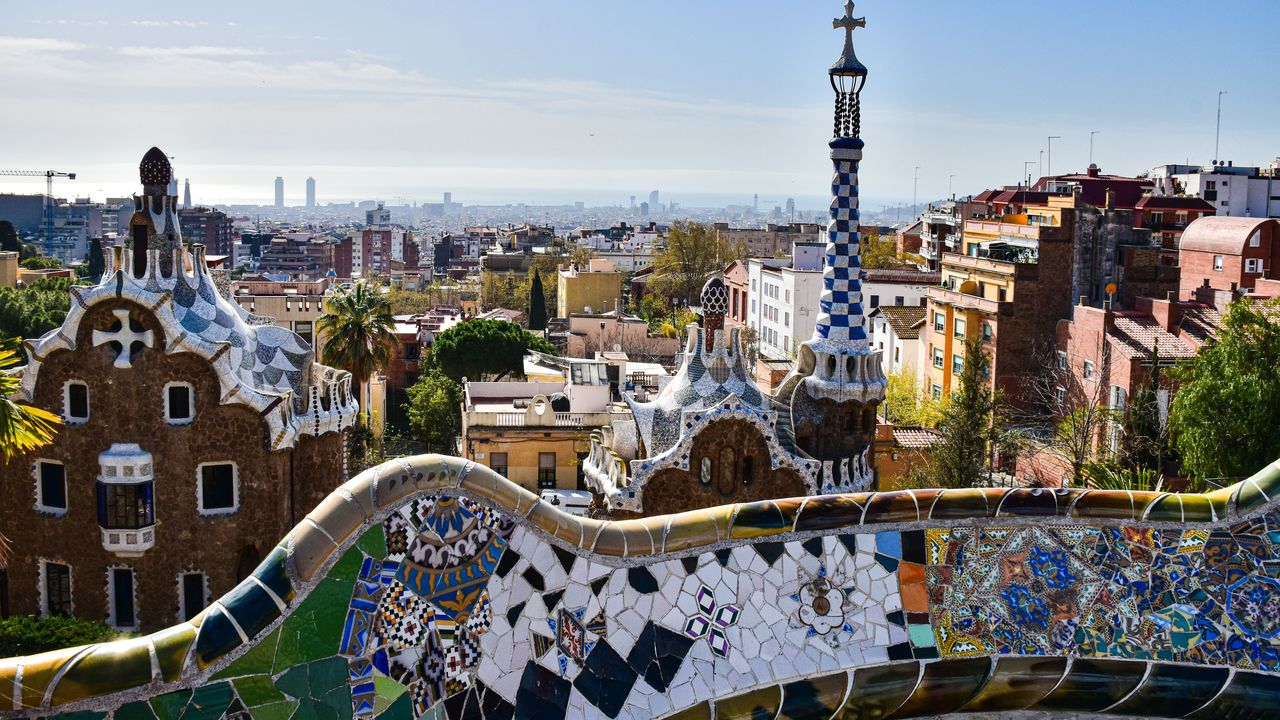 The mosaic benches of Park Güell with Barcelona spread out behind them