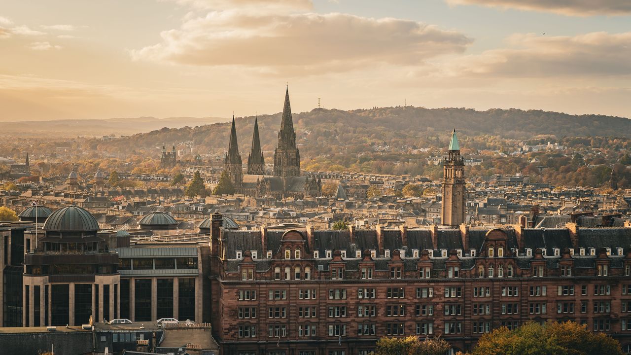 Edinburgh's old town skyline at sunset, with its spires and the hills beyond