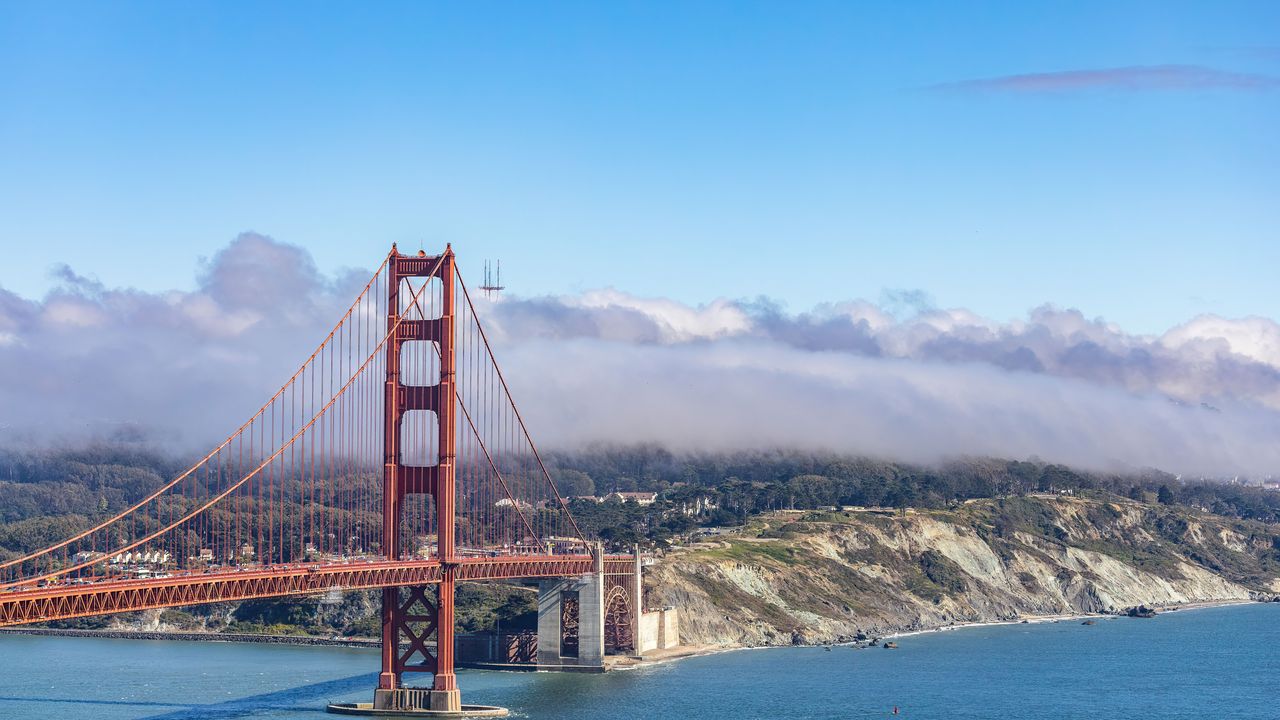 El puente Golden Gate de San Francisco bajo un cielo azul con nubes bajas sobre los cerros