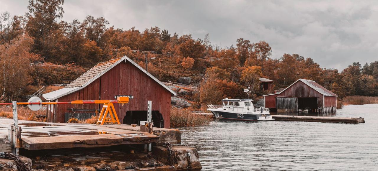 Picturesque autumn harbor scene with boat sheds and a ferry station in the Åland Islands