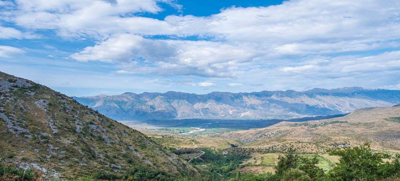 Breathtaking view of the Albanian countryside with mountains and lush valleys under a bright blue sky