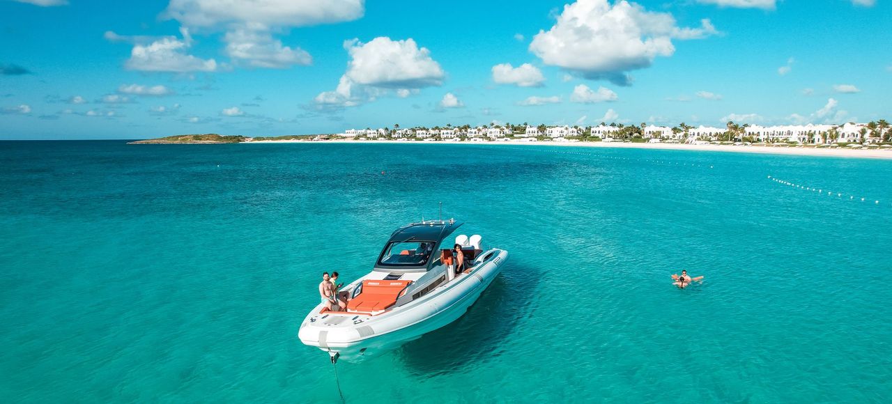 Anguilla: Aerial view of a motorboat in clear turquoise waters near a tropical beach, ideal for leisure and travel