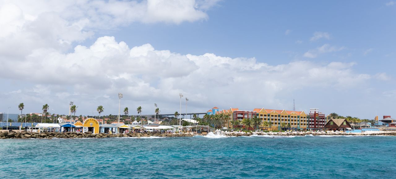 Aruba: Panoramic view of a colorful tropical resort along a crystal-clear seaside under a bright sky