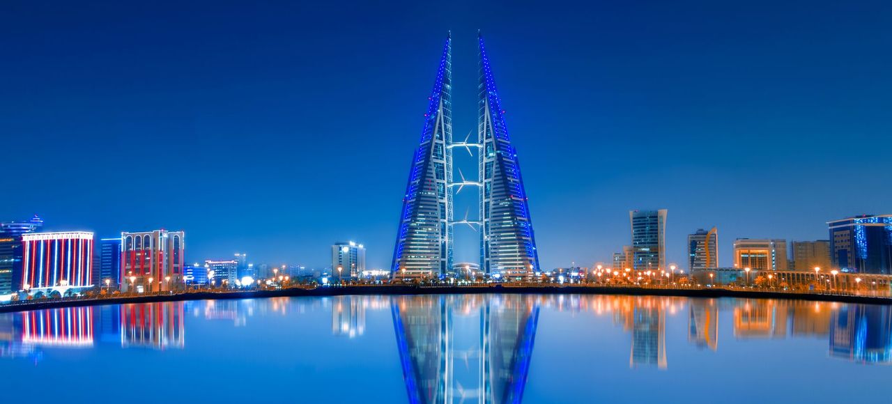Stunning night view of Bahrain World Trade Center with clear water reflections and modern skyline