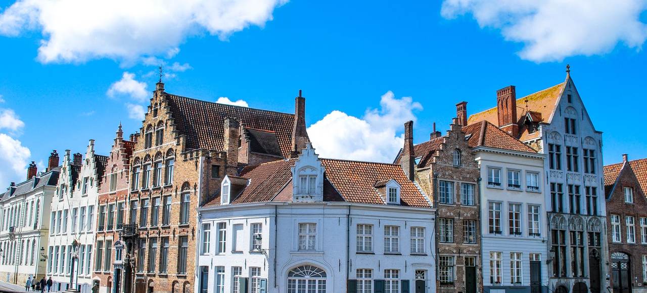 Charming townhouses along a canal in Bruges, Belgium under a vibrant blue sky