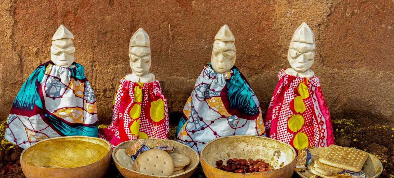 Colorful ceremonial figurines with ritual food bowls in Cotonou, Benin
