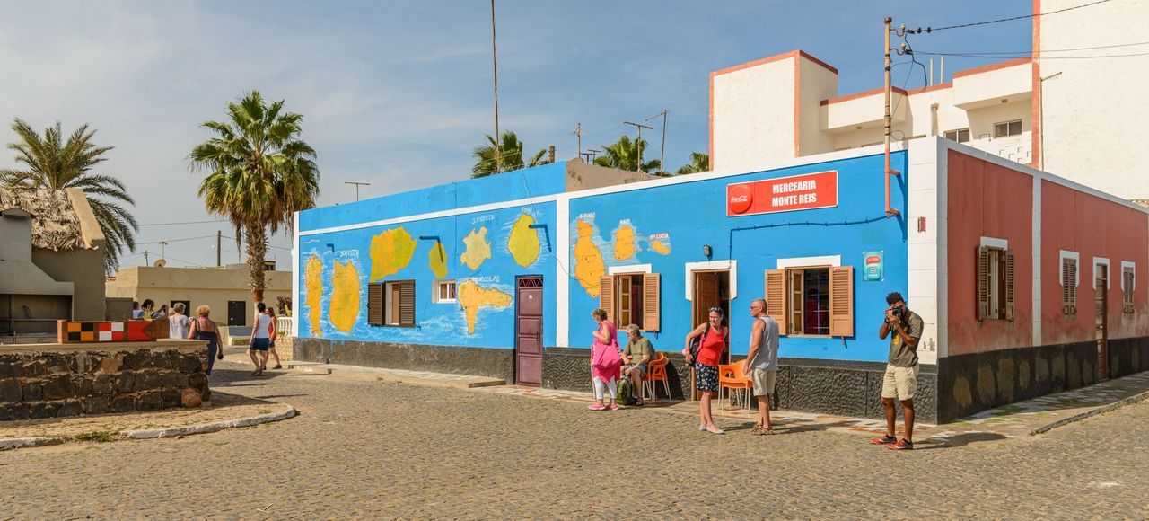 Cape Verde: Colorful street with people and mural in a sunny tropical locale