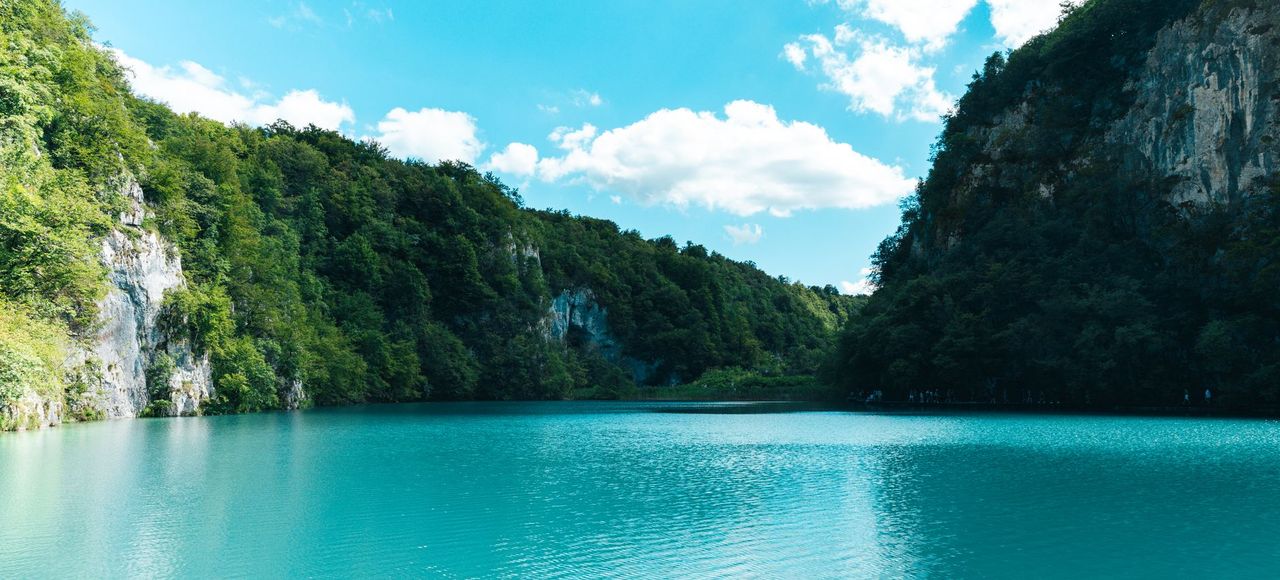 Explore the serene turquoise waters surrounded by lush greenery and cliffs in Plitvice Lakes National Park, Croatia