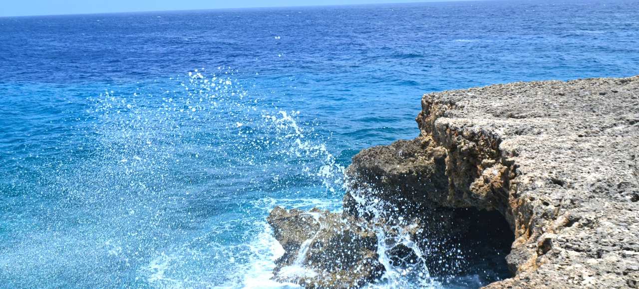 Vibrant ocean waves splashing against the rocky shoreline of Curaçao