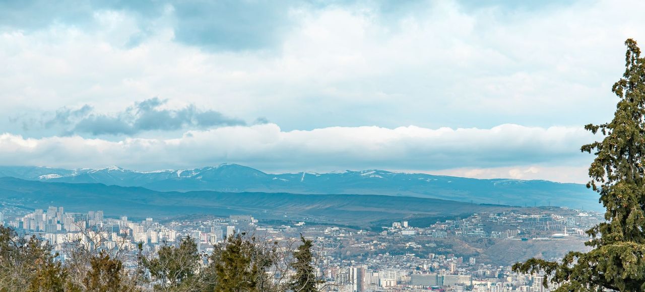 Georgia: Aerial view of Tbilisi and surrounding mountains with cloudy skies