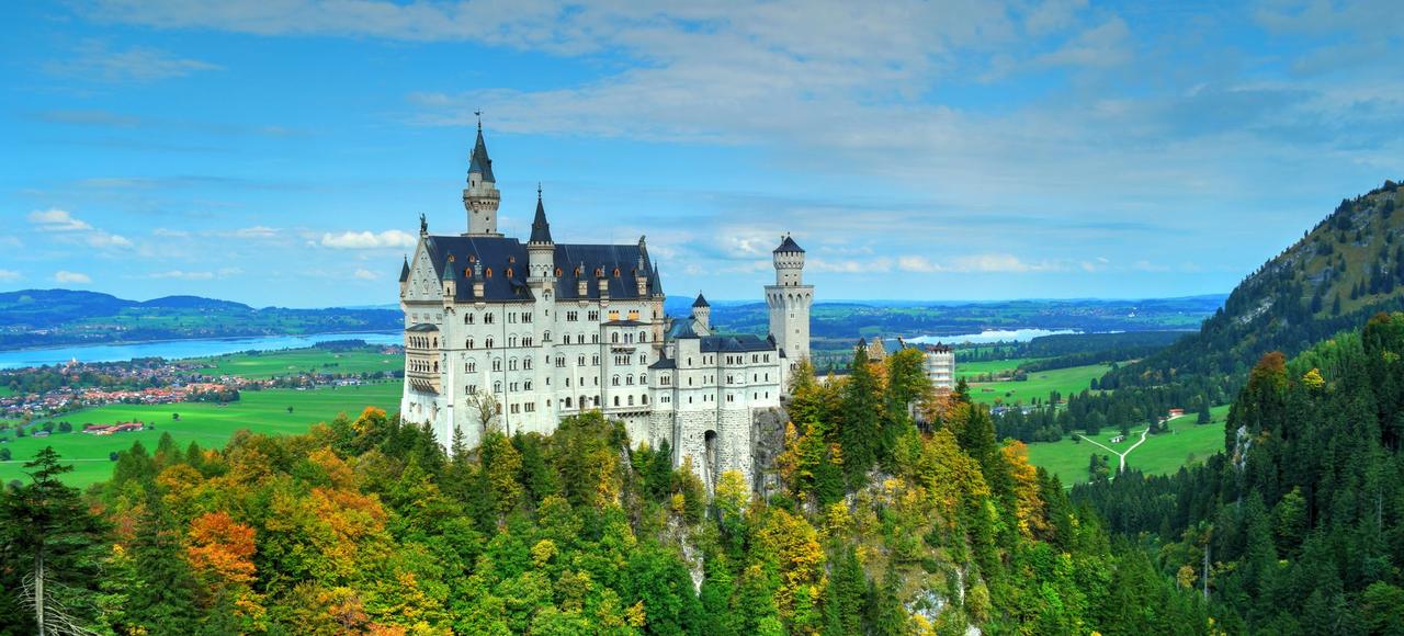 Germany: Aerial view of Neuschwanstein Castle amid vibrant autumn foliage with scenic landscape