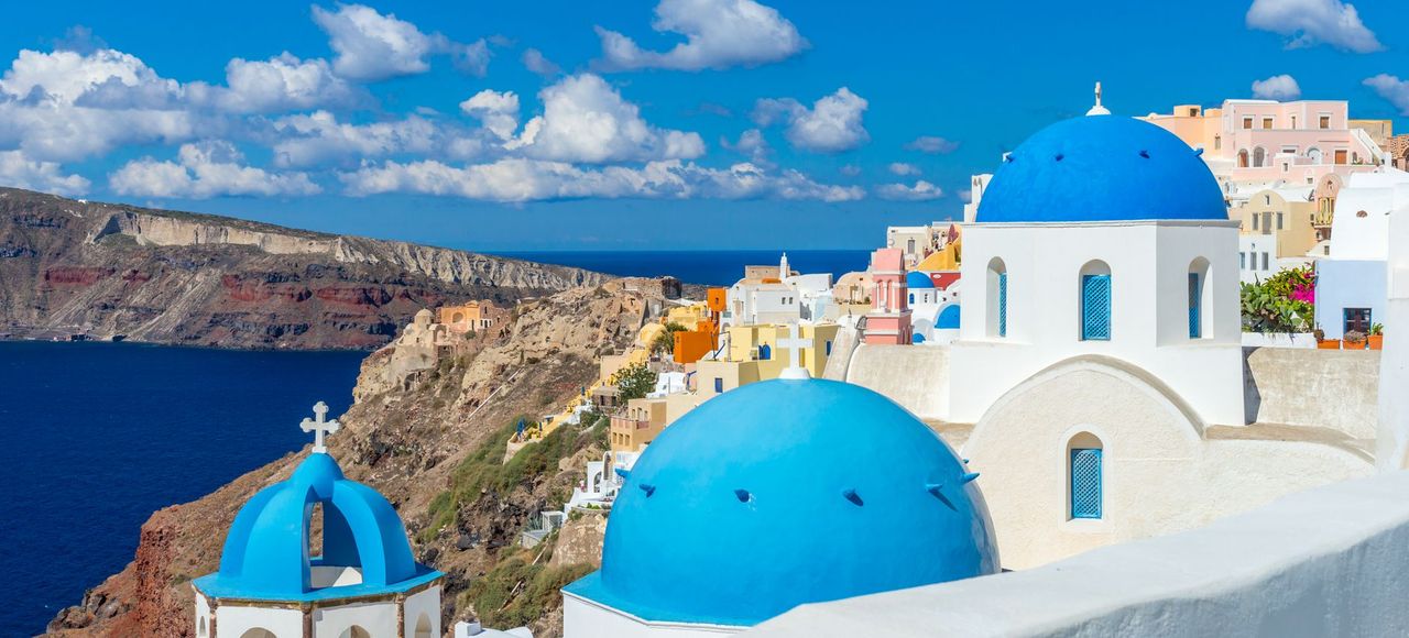 Greece: Capture the breathtaking scenery of Santorini's unique architecture and vibrant blue domes under a clear summer sky