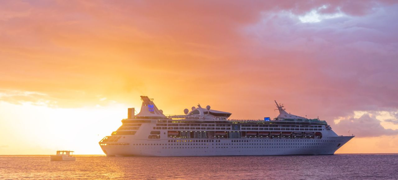 A majestic cruise ship sails at sunset off the coast of Grenada, showcasing luxury travel