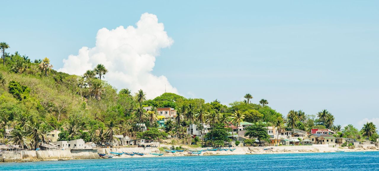 Haiti: A picturesque coastal village surrounded by lush greenery and clear blue waters under a bright sky