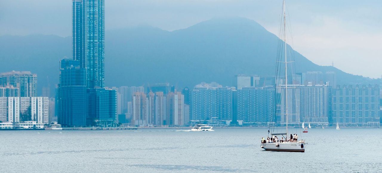 Peaceful sailboat cruising on Hong Kong Island's waterfront with city skyline backdrop