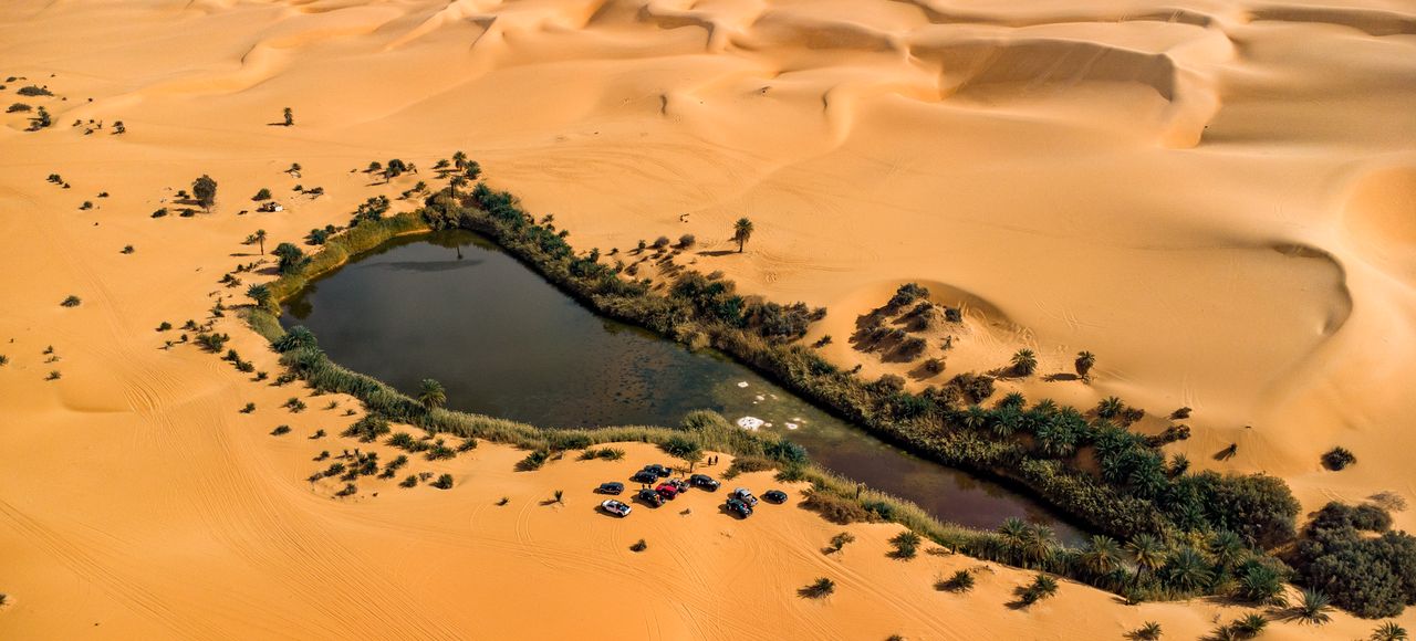 Libya: A stunning aerial view of an oasis surrounded by vast desert sand dunes