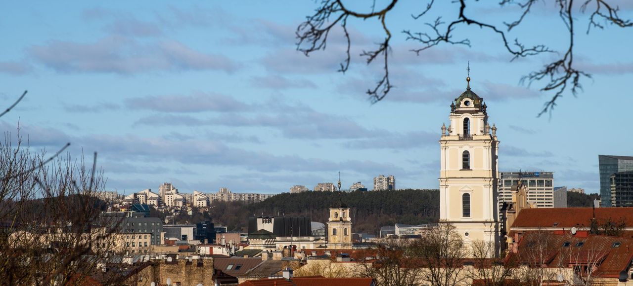 Lithuania: A beautiful view of Vilnius city featuring historic architecture and a prominent church tower under a clear sky