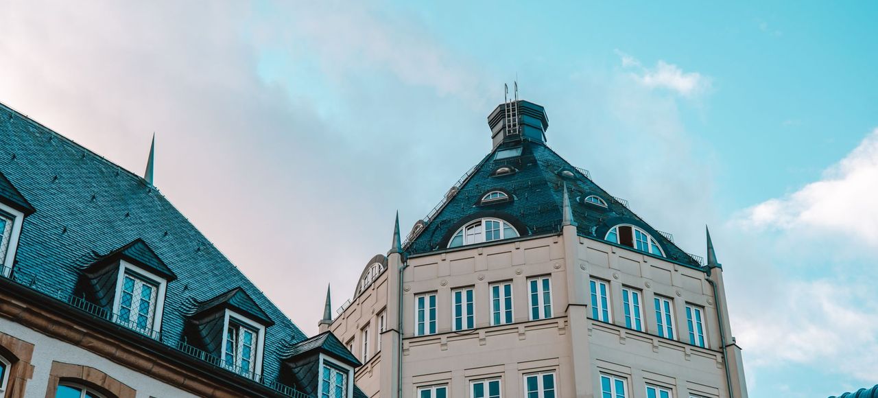 A historic building in Luxembourg stands against a striking blue sky, showcasing its unique architecture
