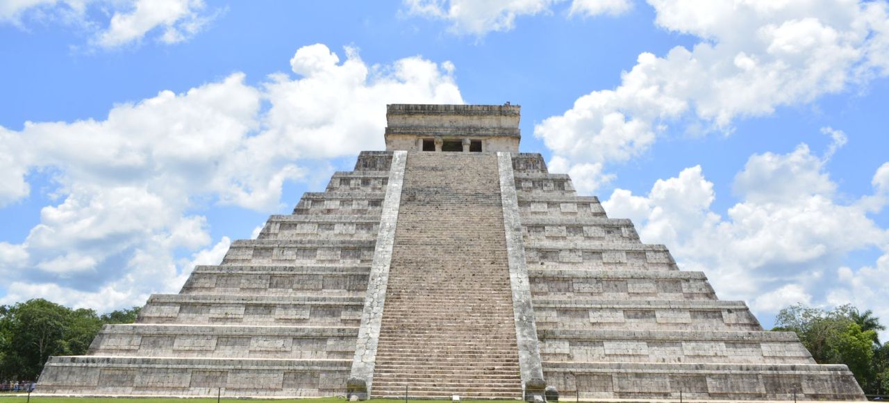 Mexico: Stunning view of the ancient Pyramid of Chichén Itzá with a bright blue sky and clouds