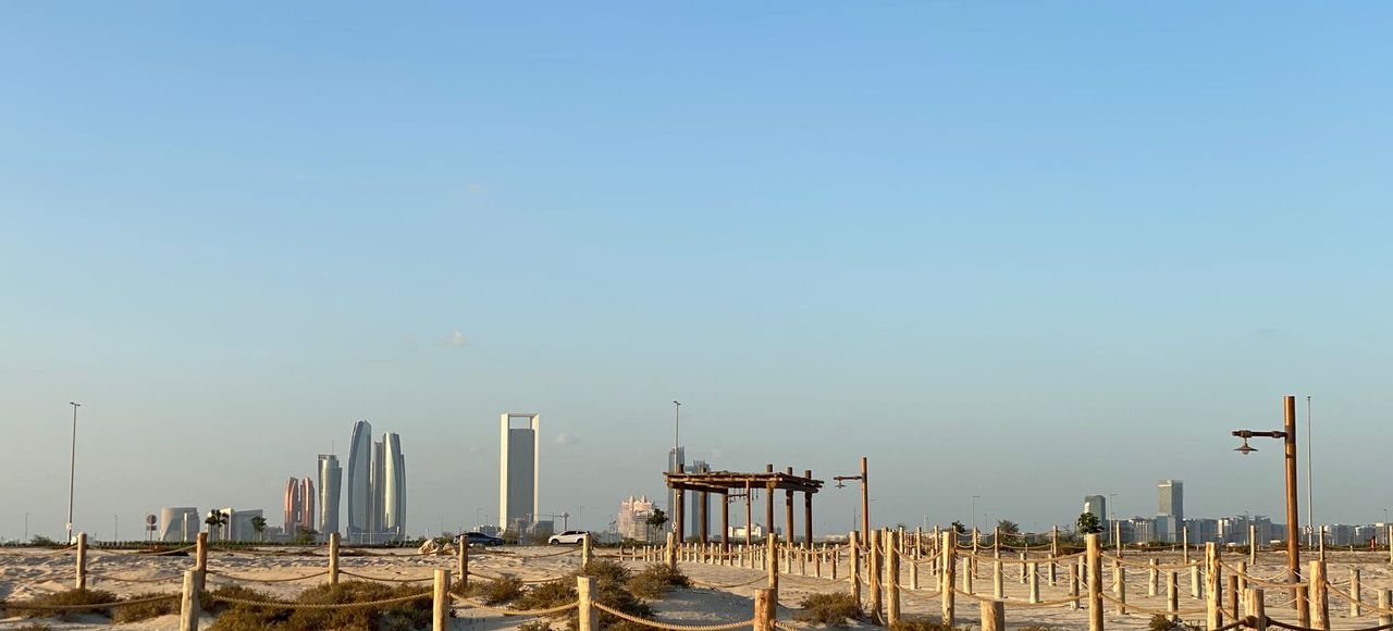 Middle East: Sunny desert landscape with Abu Dhabi skyline in the background, showcasing modern architecture and clear blue skies