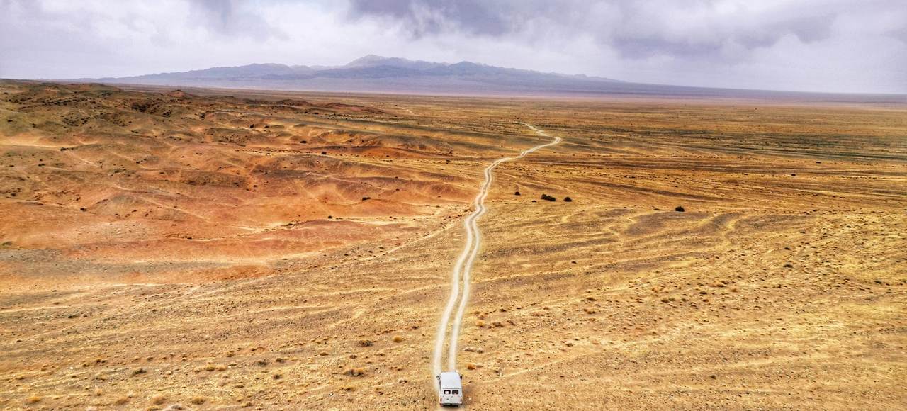 Van traveling on desolate road in Mongolian desert, an expansive, scenic landscape