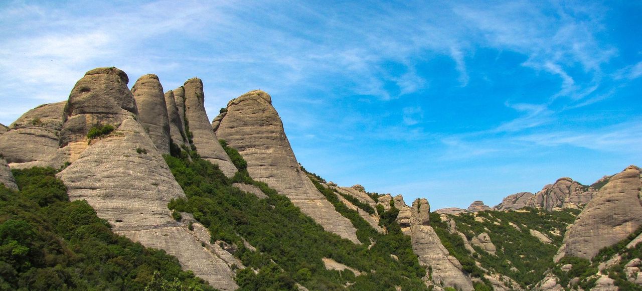 Panoramic view of Montserrat's unique rock formations against a bright blue sky