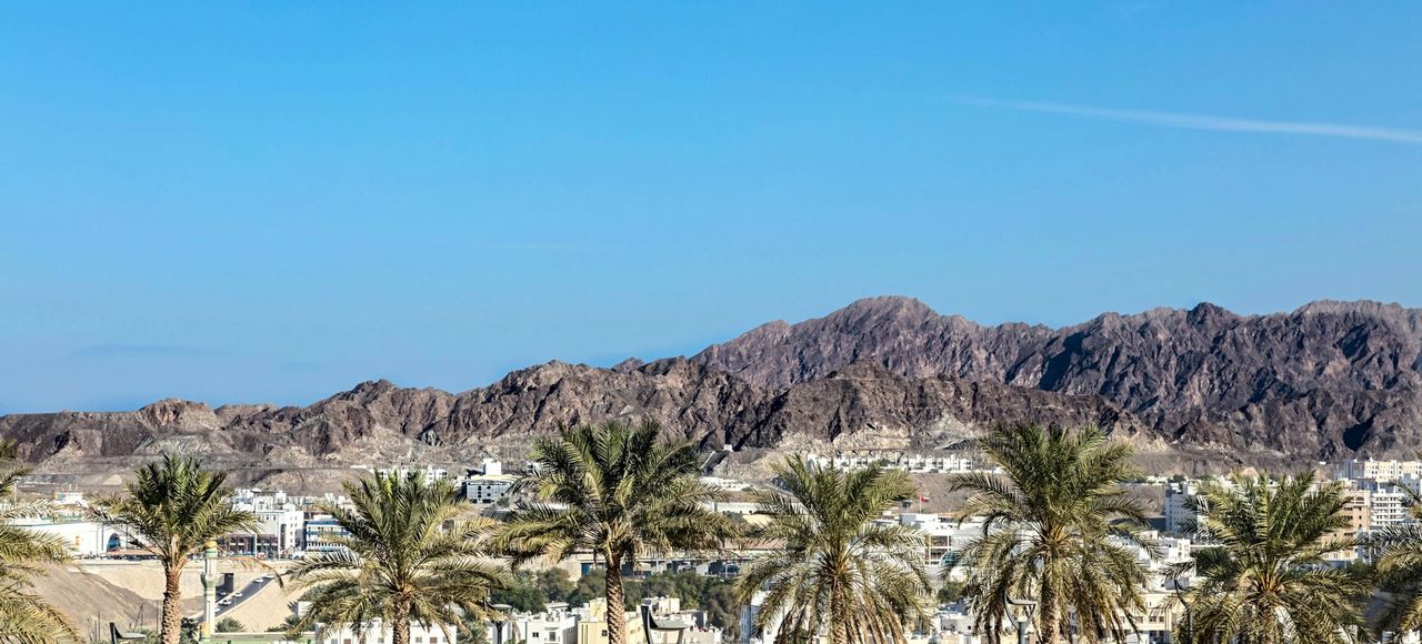 Oman: Desert mountains and palm trees under a vibrant blue sky