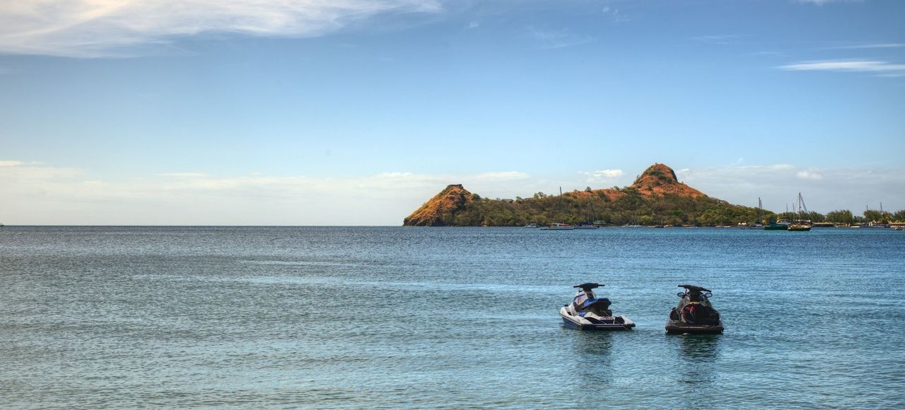 Saint Lucia: Idyllic tropical beachscape with two jet skis on calm ocean waters at sunset
