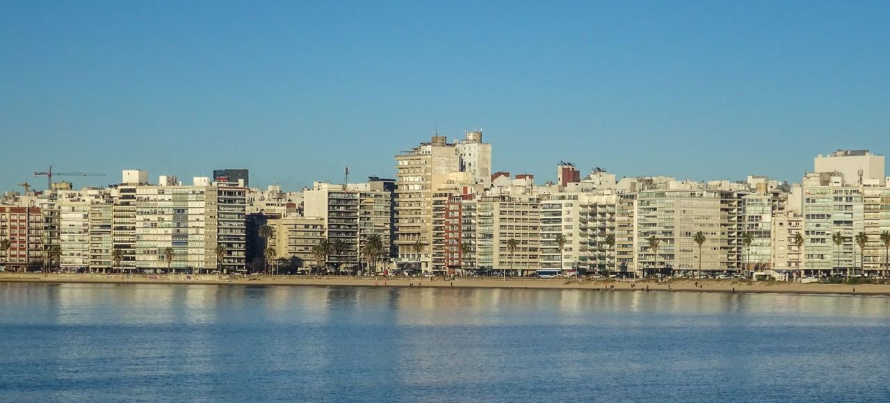 Uruguay: A serene view of Montevideo's skyline reflecting on the waterfront under a clear blue sky